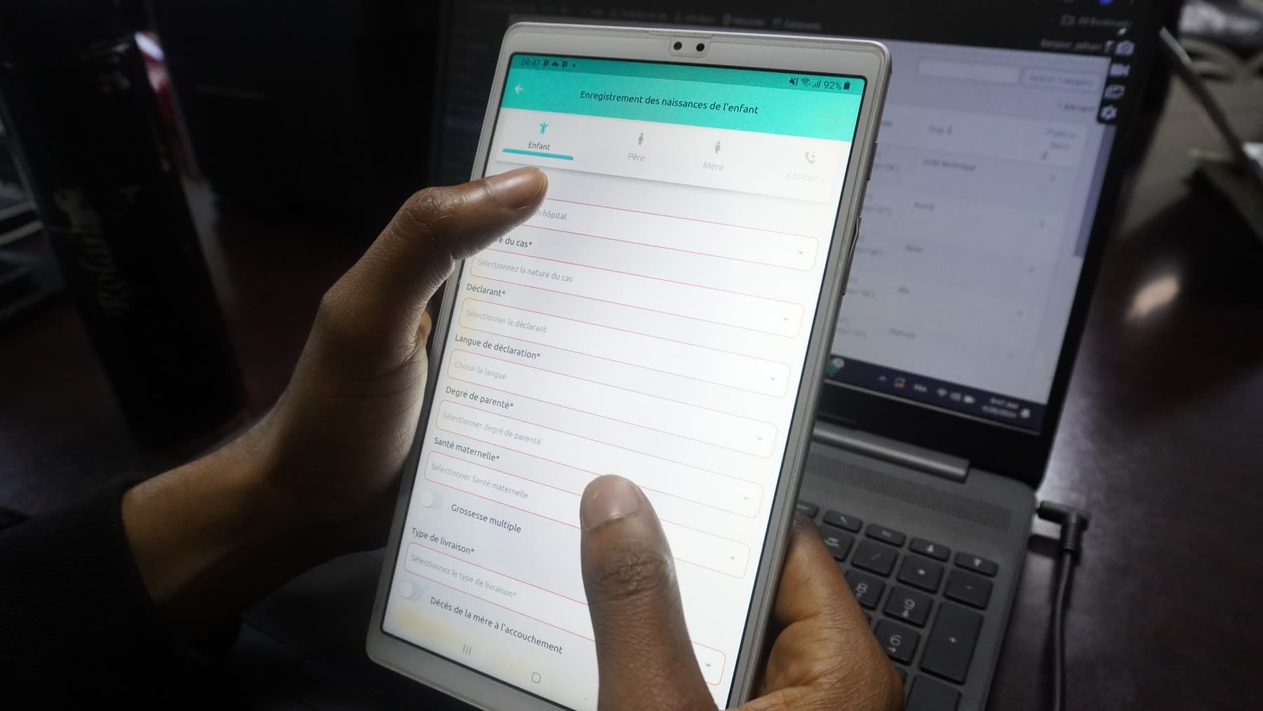 Le personnel d'eGov forme des agents de santé à la plateforme — des mains sur une tablette à côté d'un ordinateur portable